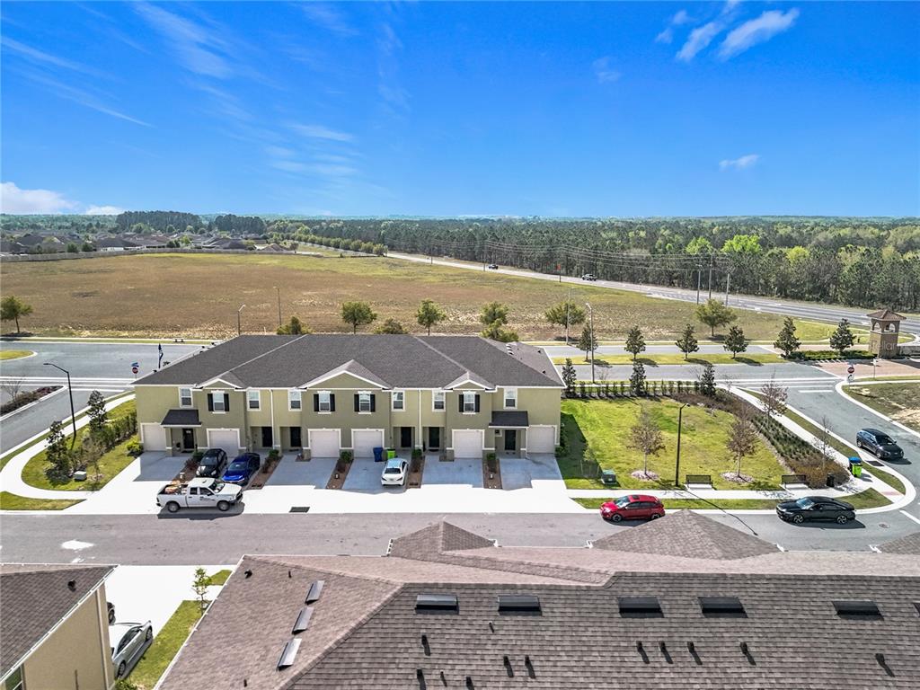 An aerial view shows a multi-unit townhouse building with a parking area and surrounding landscape — 965 LIDO DRIVE, HOWEY IN THE HILLS, FL