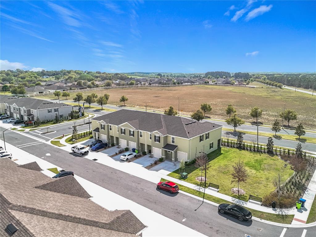An aerial view shows a light green multi-unit townhouse building with a large adjacent grassy lot — 965 LIDO DRIVE, HOWEY IN THE HILLS, FL