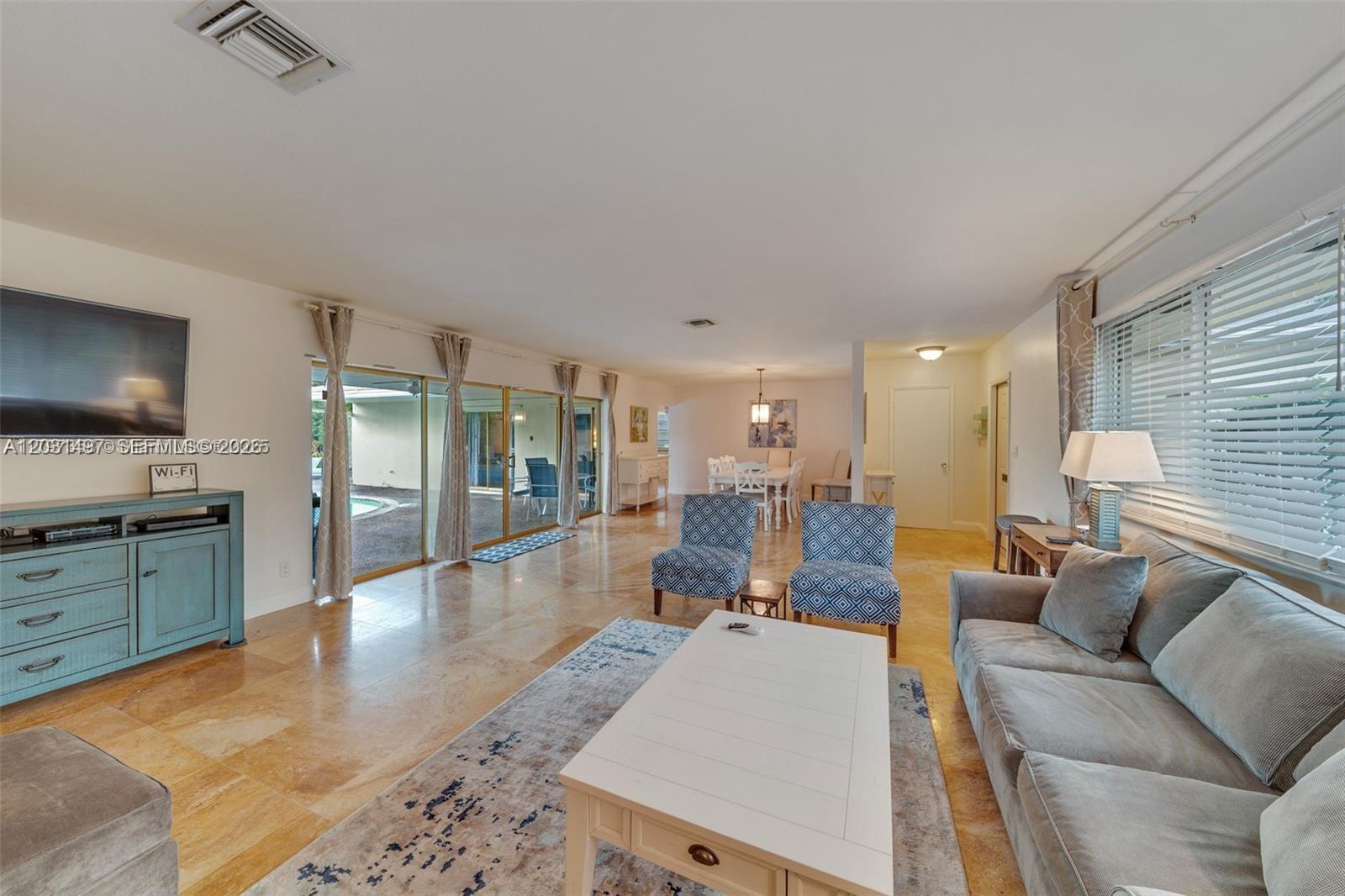A living room features tile floors, a gray sofa, patterned chairs, and sliding glass doors — 4410 N Buchanan St, Hollywood FL 33021, HOLLYWOOD, FL