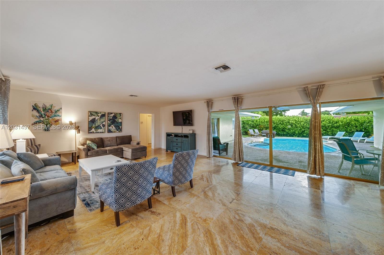 A living room with tile floors features a pool view through large sliding glass doors — 4410 N Buchanan St, Hollywood FL 33021, HOLLYWOOD, FL