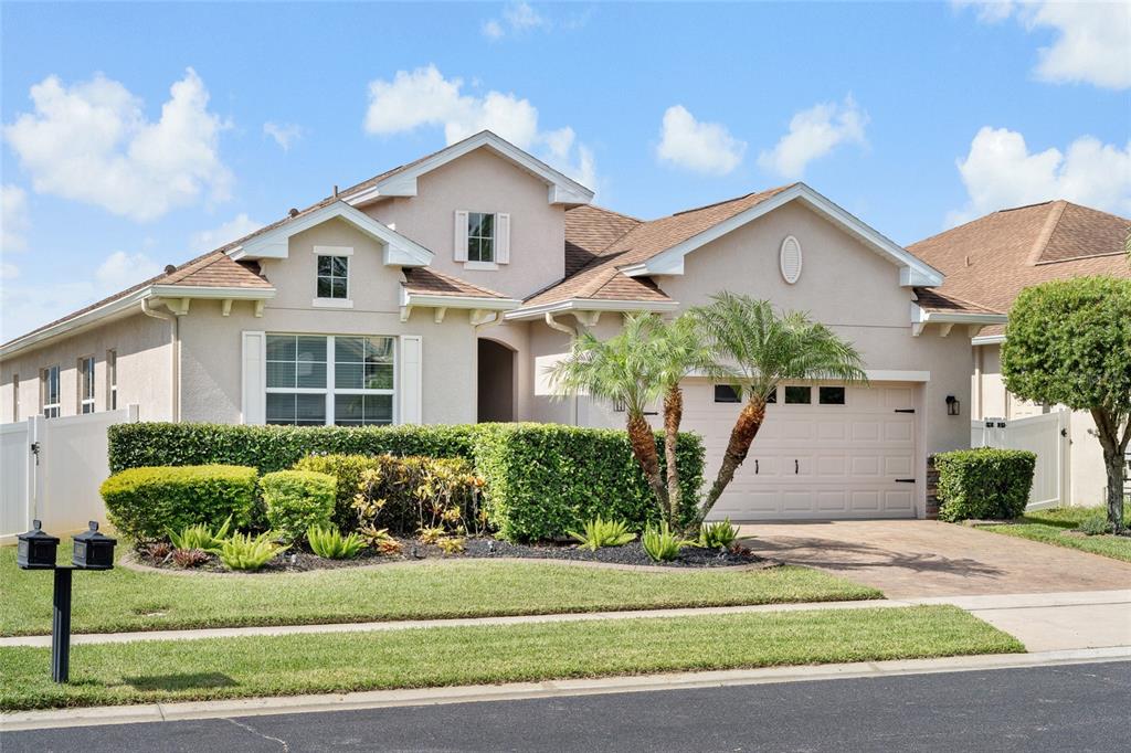 A single-story house with a beige stucco exterior, a two-car garage, and manicured landscaping — 4436 AZURE ISLE WAY, KISSIMMEE, FL