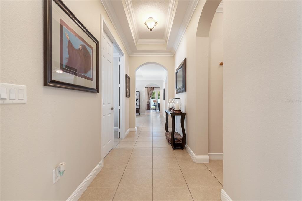 A long, tiled hallway features arched doorways, a tray ceiling, and a console table — 4436 AZURE ISLE WAY, KISSIMMEE, FL