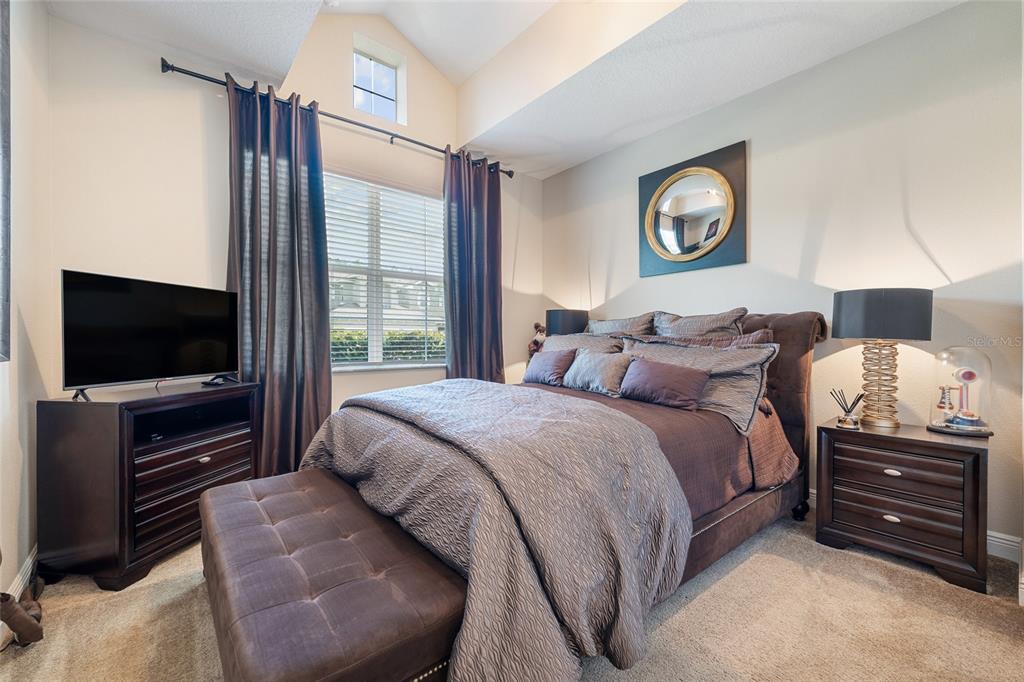 A bedroom features a queen bed, dark wood furniture, and a vaulted ceiling with windows — 4436 AZURE ISLE WAY, KISSIMMEE, FL