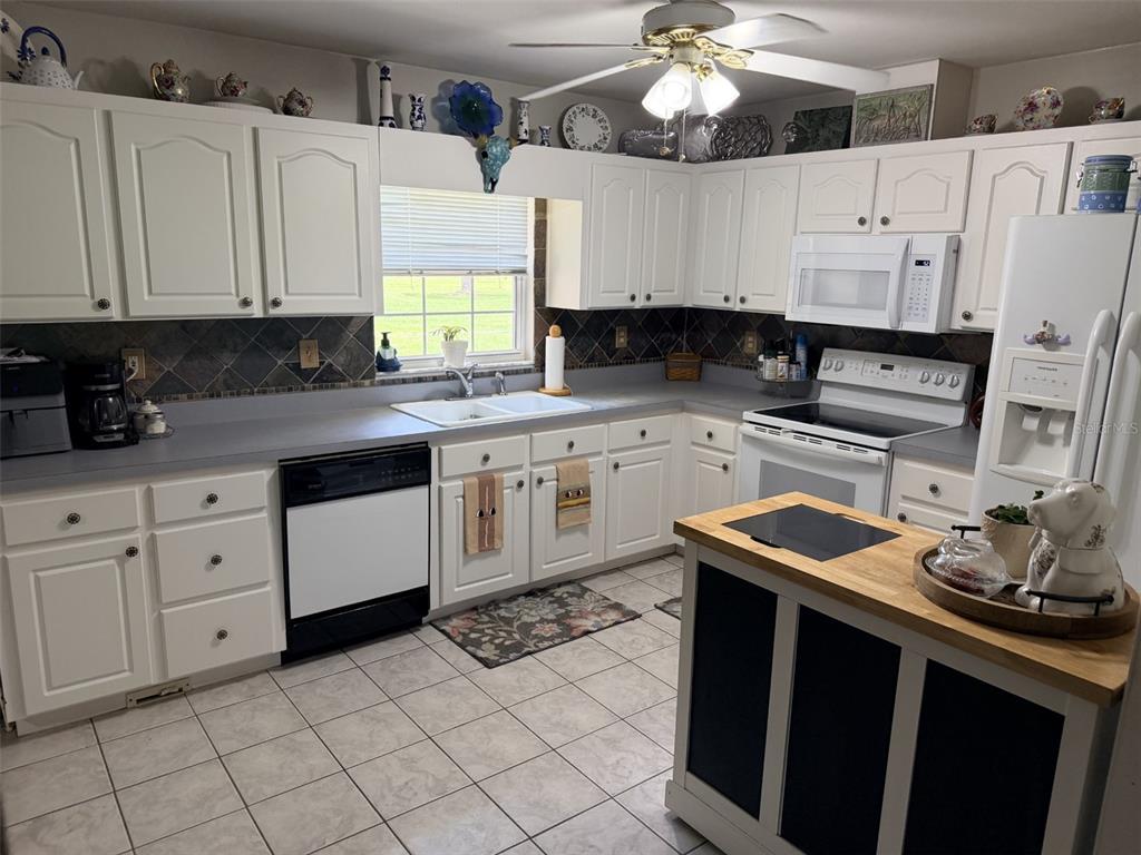 A kitchen features white cabinets, gray countertops, a center island, and a tile floor — 6051 NW 81ST PLACE, CHIEFLAND, FL