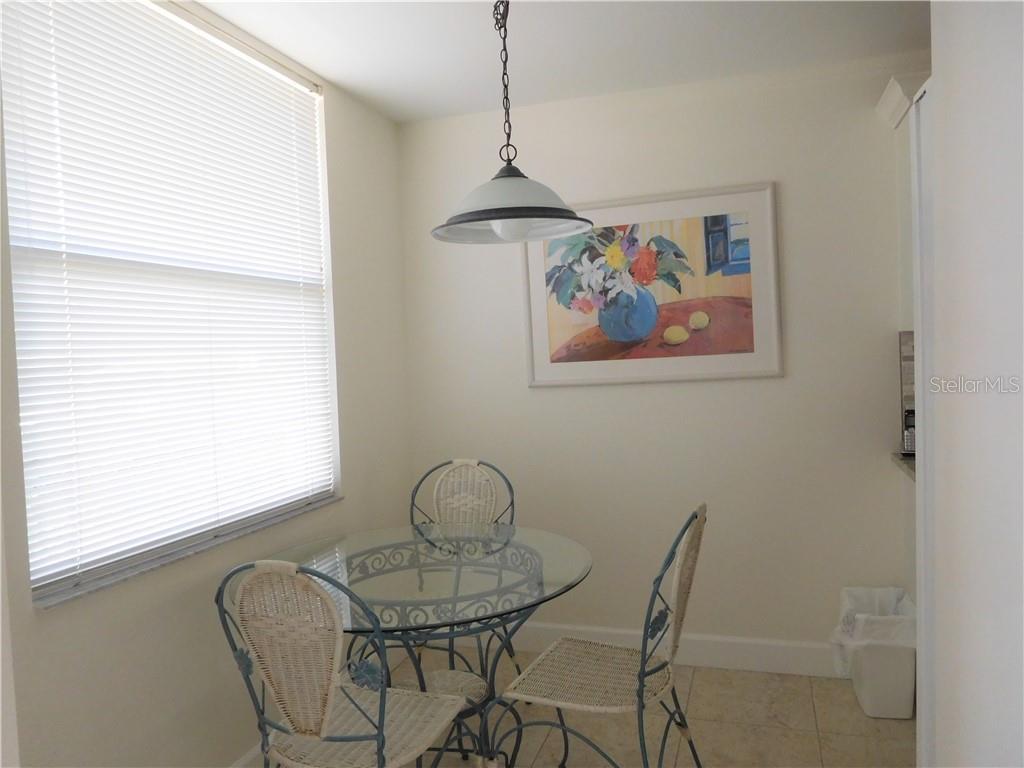 A dining area features a glass-topped table, three wicker chairs, a pendant light, and artwork — 8735 OLDE HICKORY AVENUE UNIT 8104, SARASOTA, FL