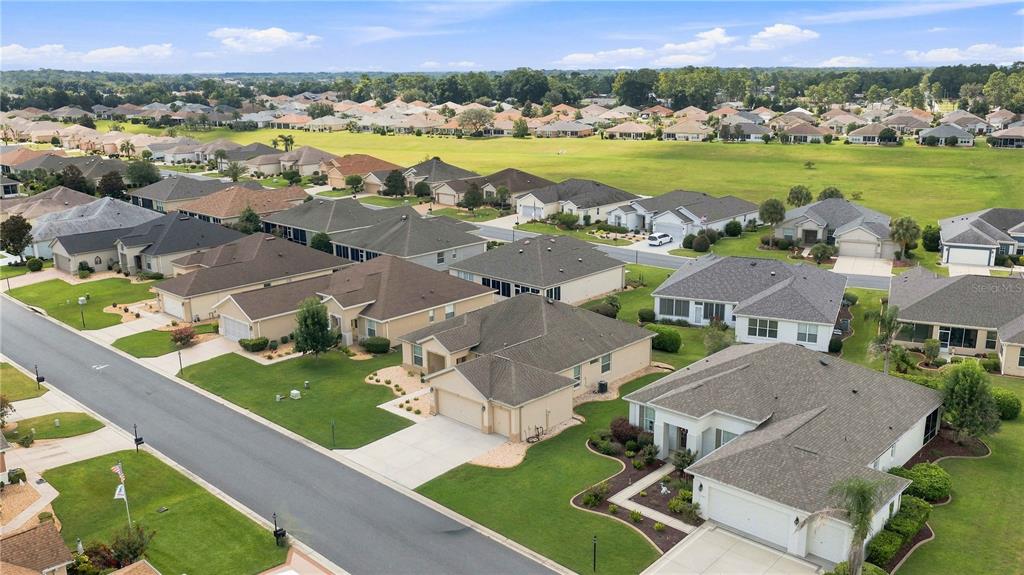 An aerial view shows a suburban neighborhood with single-family homes and a large grassy field — 11811 SE 91ST CIRCLE, SUMMERFIELD, FL