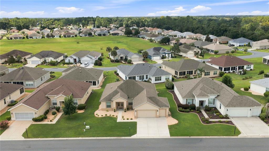 An aerial view shows a suburban neighborhood with single-family homes, manicured lawns, and paved streets — 11811 SE 91ST CIRCLE, SUMMERFIELD, FL