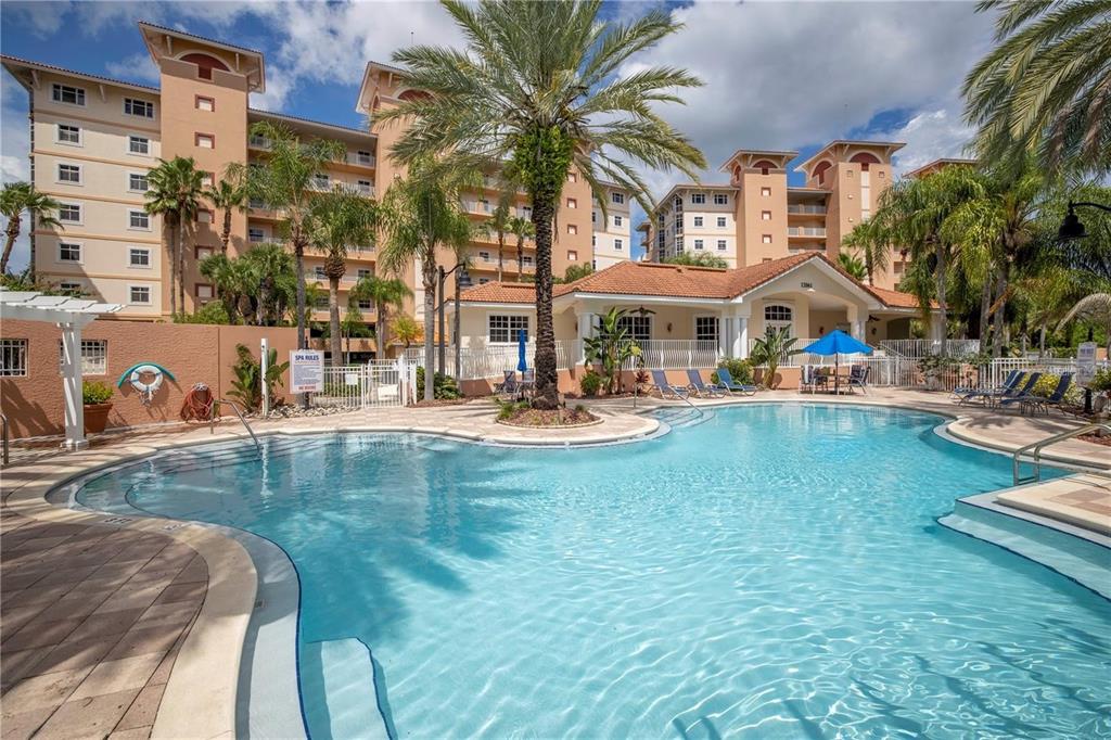 A swimming pool sits in front of a multi-story apartment building with palm trees — 12077 GANDY BOULEVARD N UNIT 332, ST PETERSBURG, FL