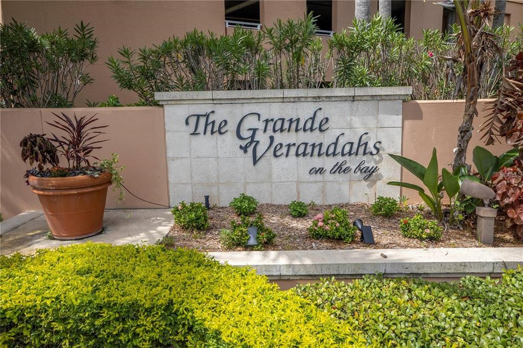 A stone monument sign for The Grande Verandahs on the bay sits in a garden — 12077 GANDY BOULEVARD N UNIT 332, ST PETERSBURG, FL