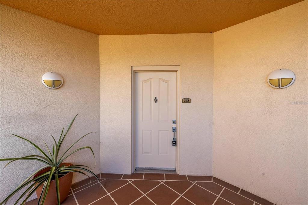 A white front door with a house number is centered on a tiled porch — 12077 GANDY BOULEVARD N UNIT 332, ST PETERSBURG, FL