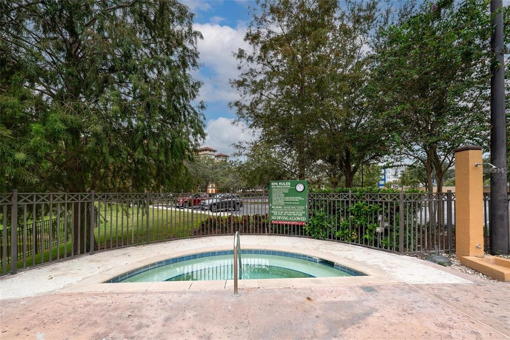An outdoor hot tub is enclosed by a metal fence with trees in the background — 12544 FLORIDAYS RESORT DRIVE UNIT 402B, ORLANDO, FL