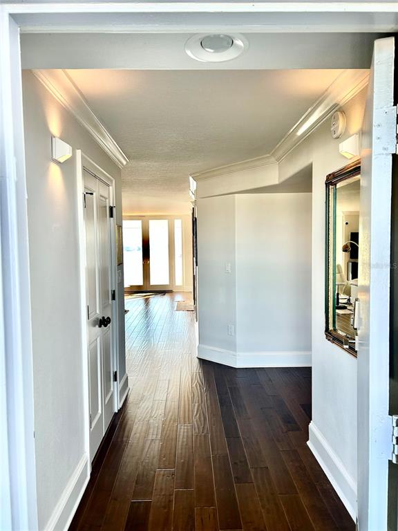 A hallway with dark wood flooring leads toward a bright room with glass doors — 1100 S ORLANDO AVENUE UNIT 956, MAITLAND, FL