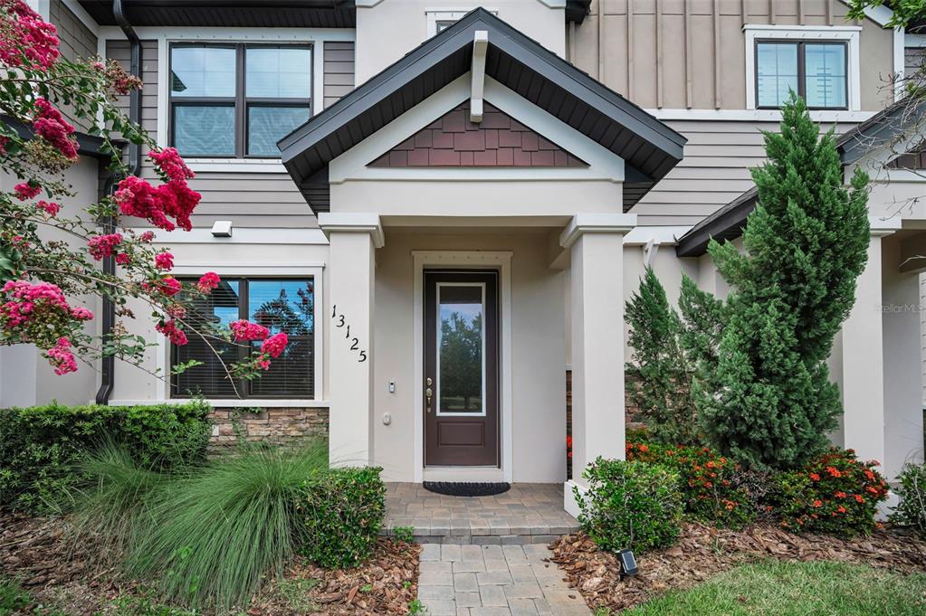 The exterior of a two-story home features a covered entryway with a brown front door — 13125 BATTEN LANE, ODESSA, FL