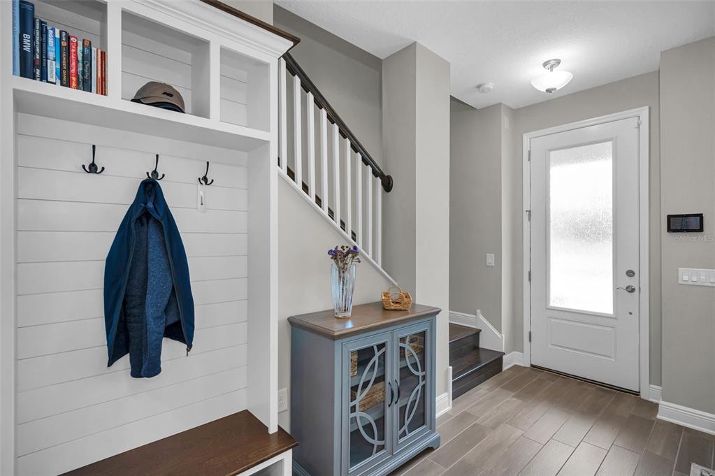 An entryway features a white built-in mudroom bench, a blue cabinet, and a staircase — 13125 BATTEN LANE, ODESSA, FL