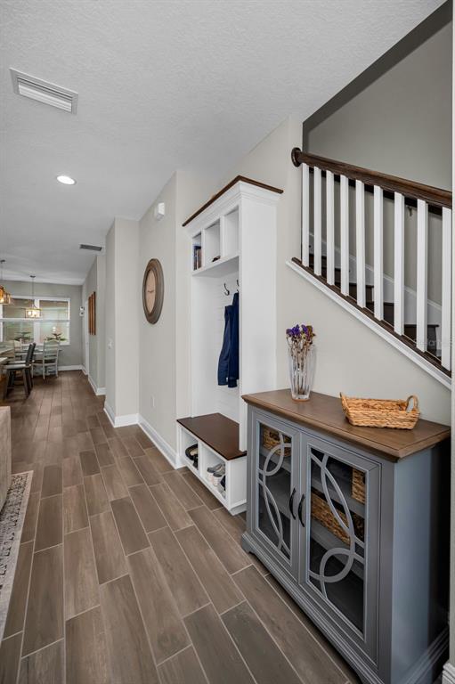 An entryway features wood-look tile flooring, a white built-in hall tree, and a gray cabinet — 13125 BATTEN LANE, ODESSA, FL