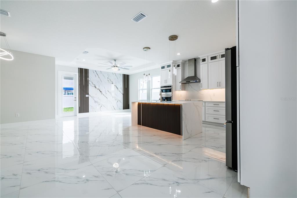 A modern open-concept kitchen and living area featuring white marble floors and a waterfall island — 3803 W PALMETTO STREET, TAMPA, FL