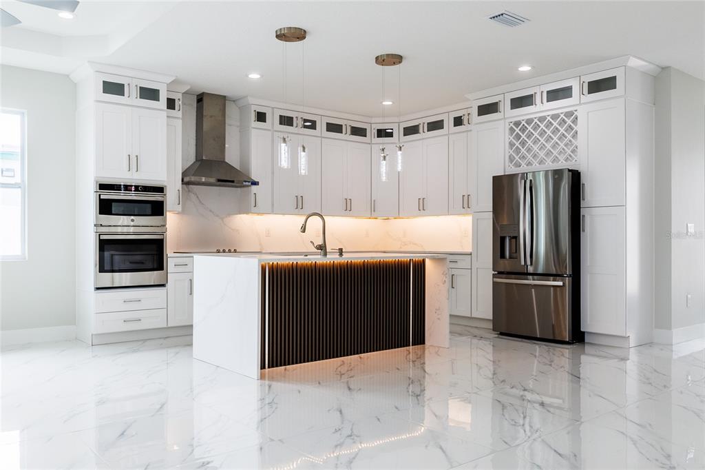 A modern kitchen features white cabinetry, a marble-topped island with slatted wood, and stainless appliances — 3803 W PALMETTO STREET, TAMPA, FL