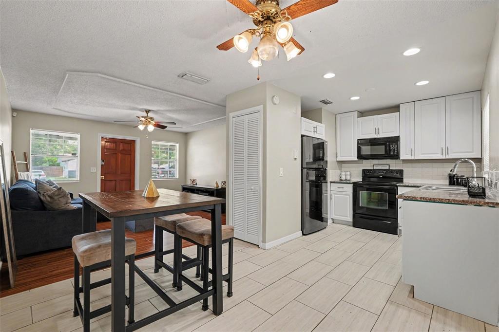 An open-concept kitchen and dining area features white cabinets, black appliances, and tile flooring — 4419 DOLPHIN DR, TAMPA, FL