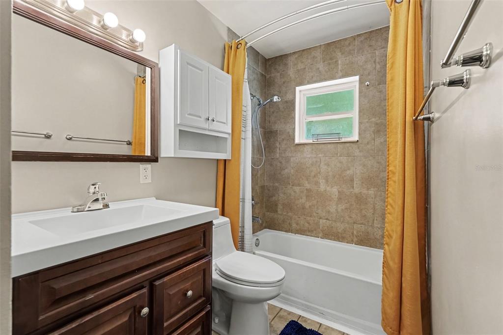A bathroom features a dark wood vanity, a white toilet, and a tiled shower-tub combination — 4419 DOLPHIN DR, TAMPA, FL