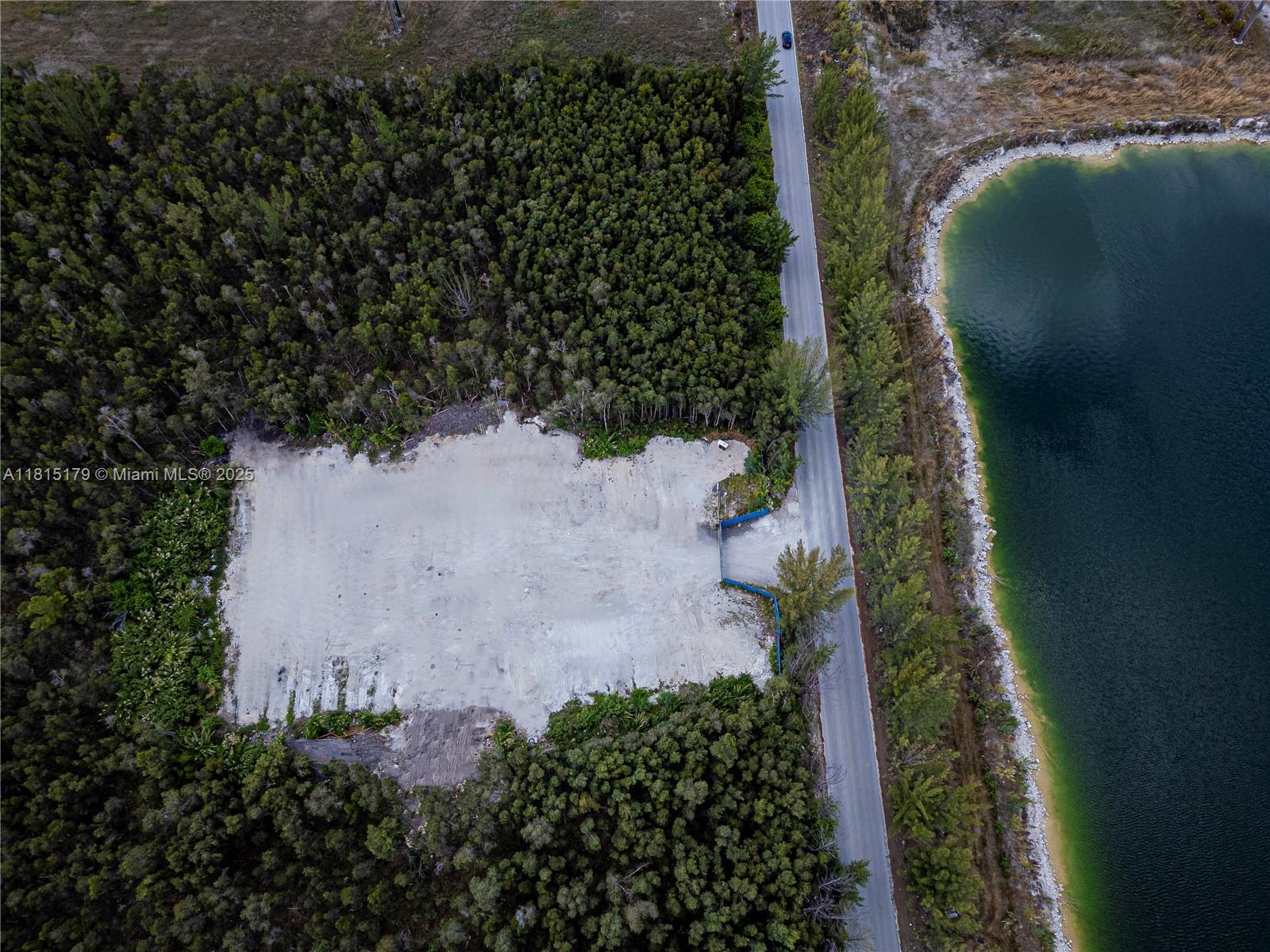 An aerial view shows a cleared rectangular lot bordered by dense forest and a lake — NW 122 Ave, NW 50 ST, Doral FL 33178, DORAL, FL