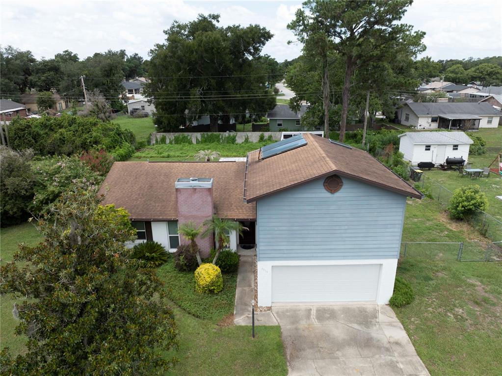 An aerial view of a two-story house with a blue exterior, brick chimney, and garage — 7316 HIGHLAND GROVE DRIVE, LAKELAND, FL