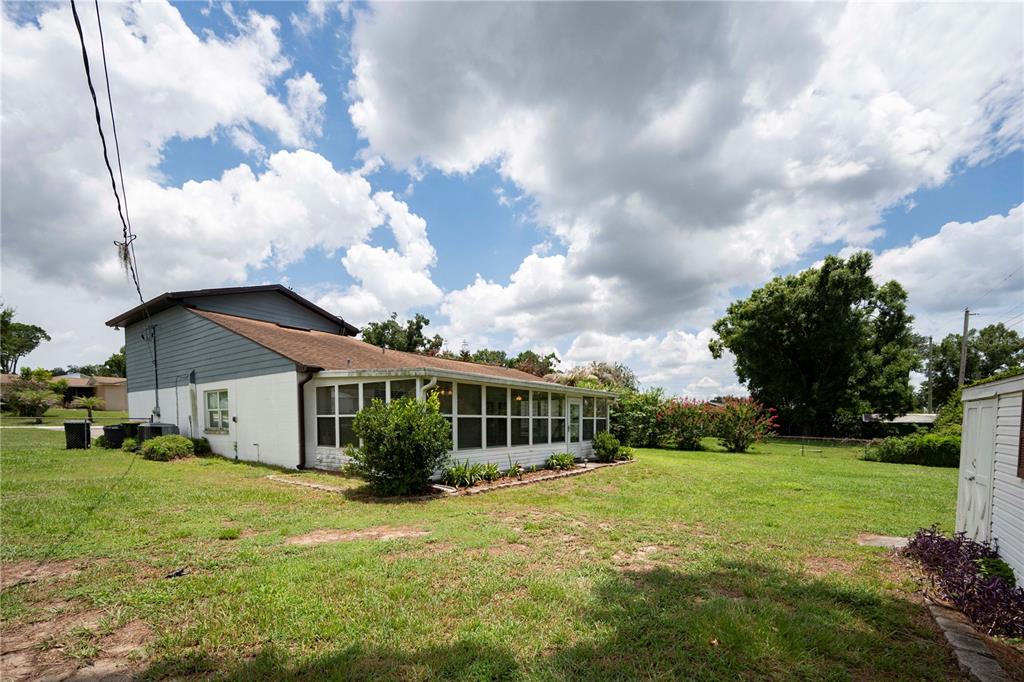 The exterior of a house features a white brick lower level, gray siding, and a sunroom — 7316 HIGHLAND GROVE DRIVE, LAKELAND, FL