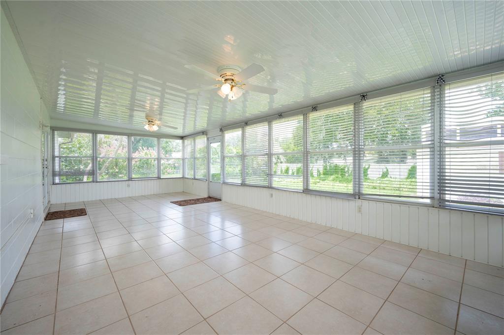 A sunroom with white tiled flooring, a beadboard ceiling, ceiling fans, and many windows — 7316 HIGHLAND GROVE DRIVE, LAKELAND, FL