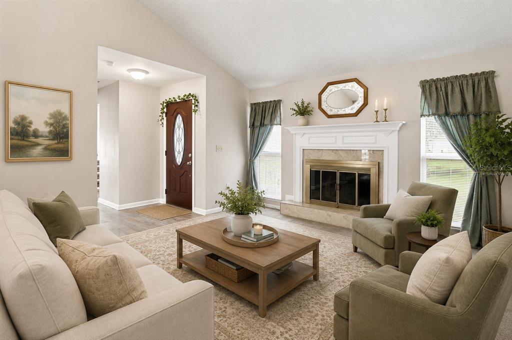 A living room features a fireplace, a coffee table, and seating arranged on a rug — 7316 HIGHLAND GROVE DRIVE, LAKELAND, FL