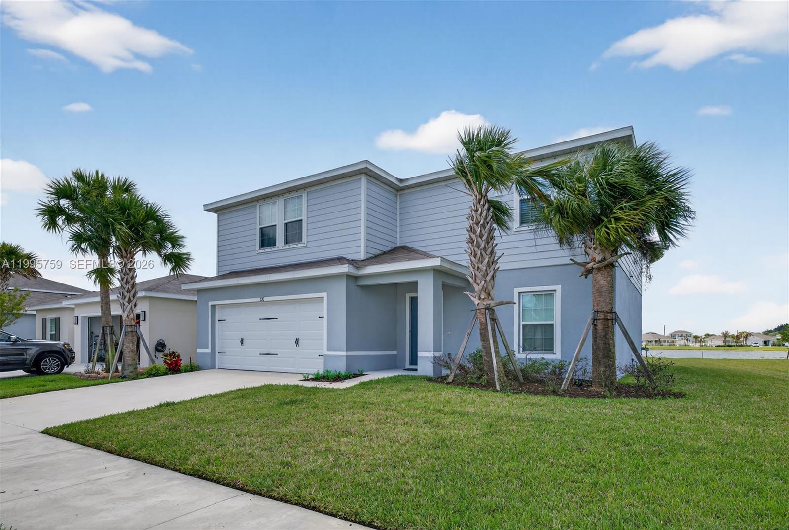 A two-story light blue house with a two-car garage and two palm trees in front — 220 Raspberry Rd, Fort Pierce FL 34981, FORT PIERCE, FL
