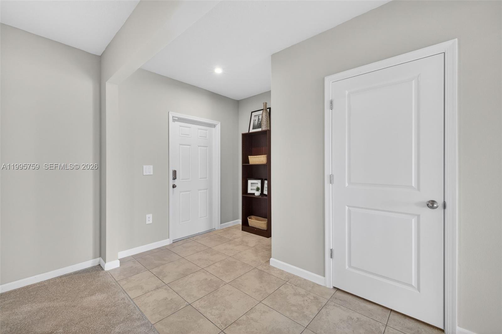 An entryway features beige tile flooring, a white front door, and a dark wood bookshelf — 220 Raspberry Rd, Fort Pierce FL 34981, FORT PIERCE, FL