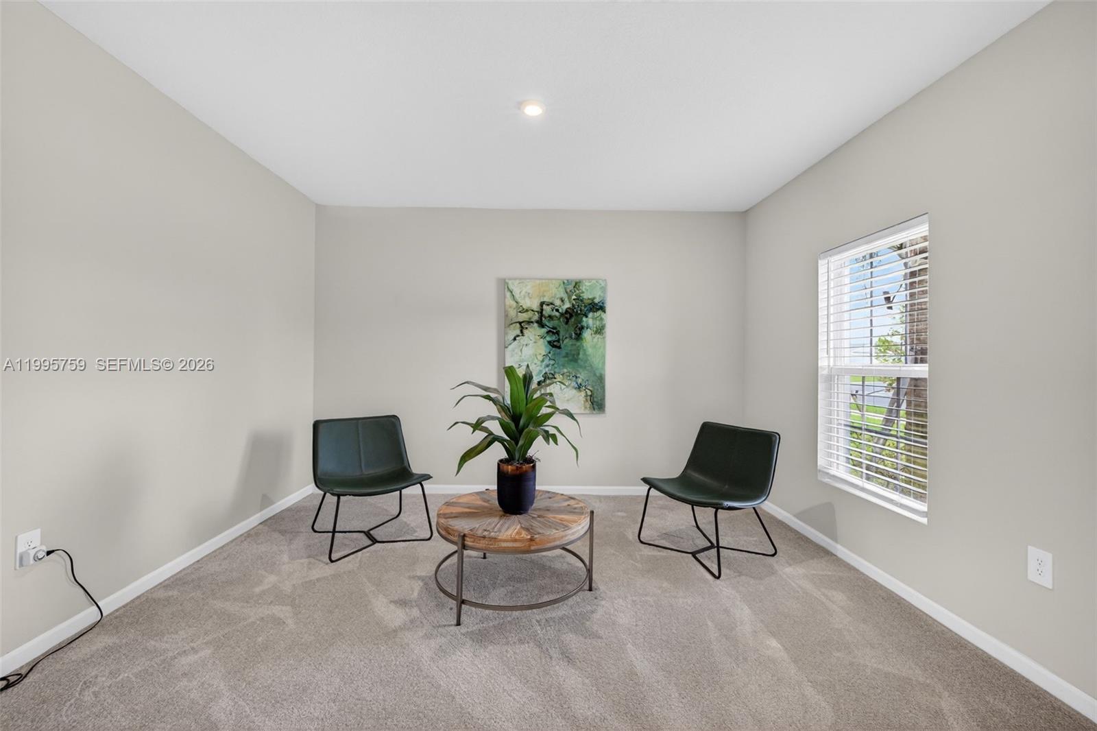 A carpeted room features two dark chairs, a round wooden coffee table, and wall art — 220 Raspberry Rd, Fort Pierce FL 34981, FORT PIERCE, FL
