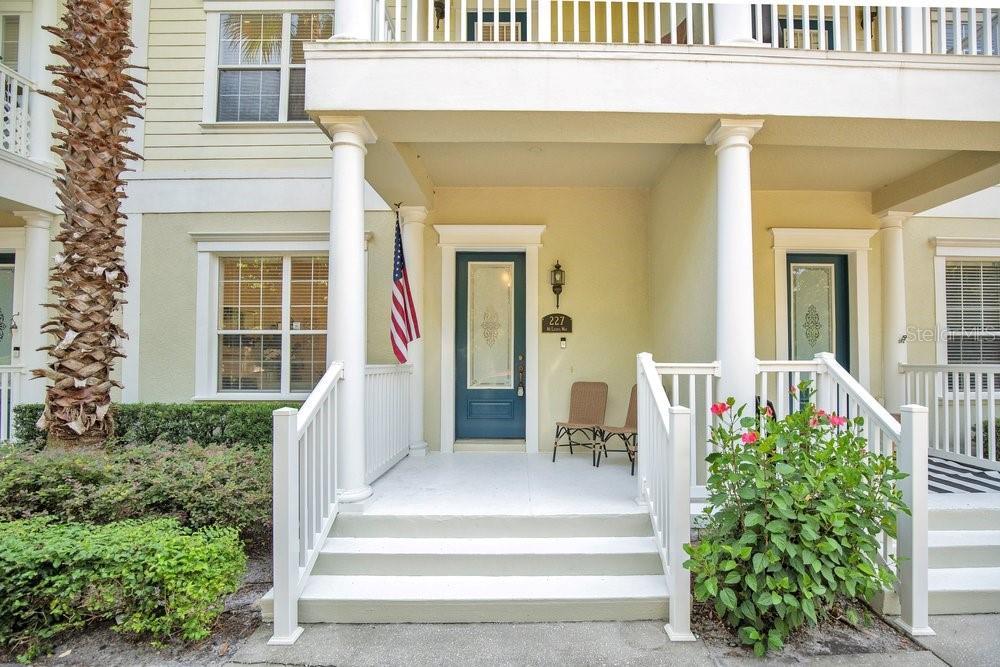 A front porch with white railings, stairs, and a blue door with an American flag — 227 MCLEODS WAY, WINTER SPRINGS, FL