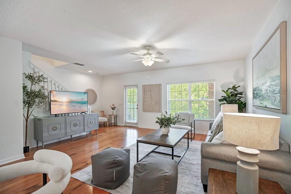 An open-concept living and dining area features hardwood floors, a gray sofa, and wooden cabinetry — 227 MCLEODS WAY, WINTER SPRINGS, FL