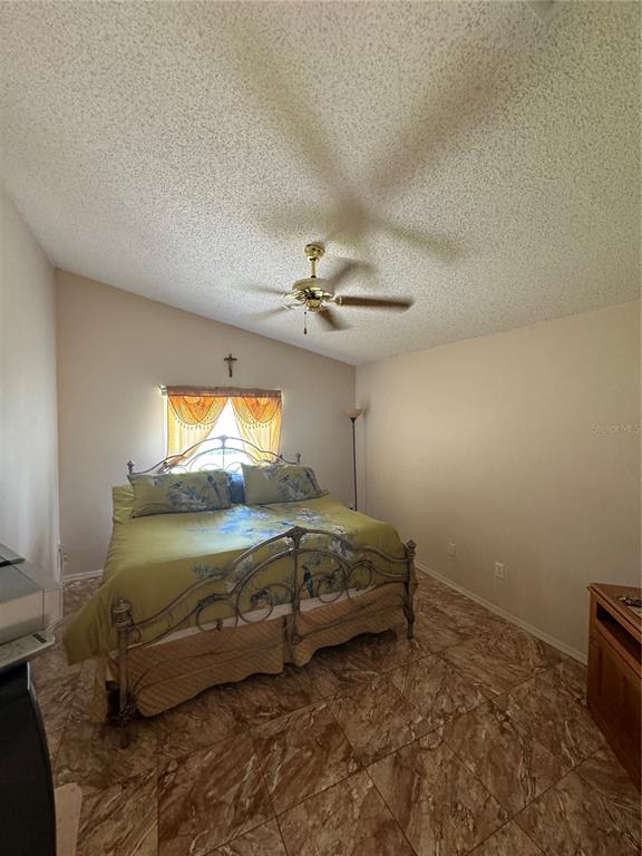 A bedroom with a vaulted ceiling, a ceiling fan, tile flooring, and a metal bed frame — 105 CATTAIL COURT, KISSIMMEE, FL