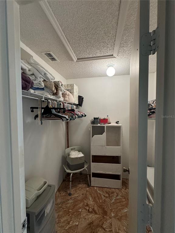 A walk-in closet features a hanging rod, shelving, a small cabinet, and tile flooring — 105 CATTAIL COURT, KISSIMMEE, FL