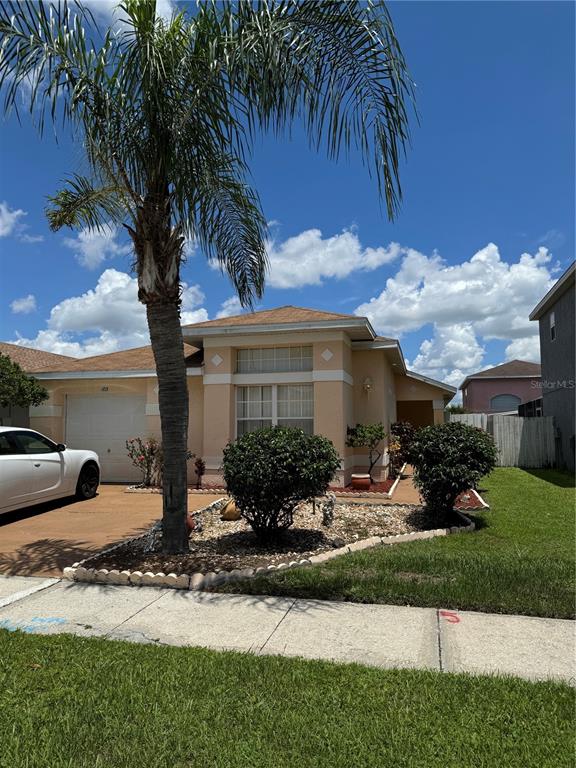 A tan single-story house features a palm tree, a white car, and a landscaped yard — 105 CATTAIL COURT, KISSIMMEE, FL