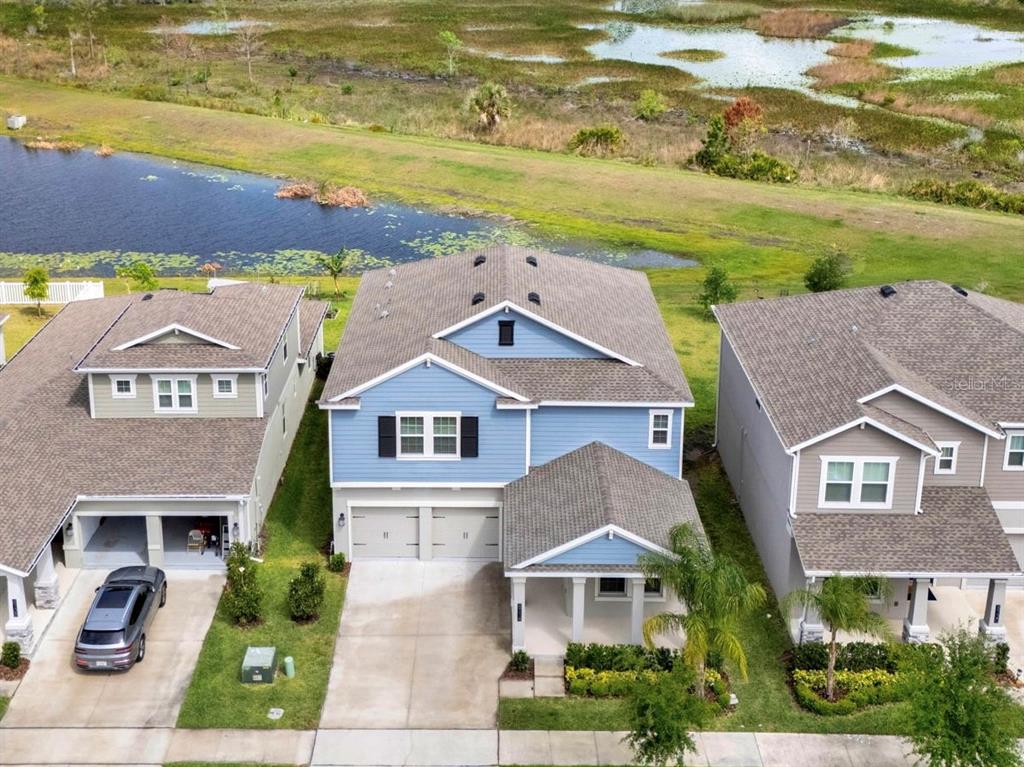 An aerial view shows a blue two-story house situated between two neighboring homes near water — 8114 SAYINGS DRIVE, WINTER GARDEN, FL
