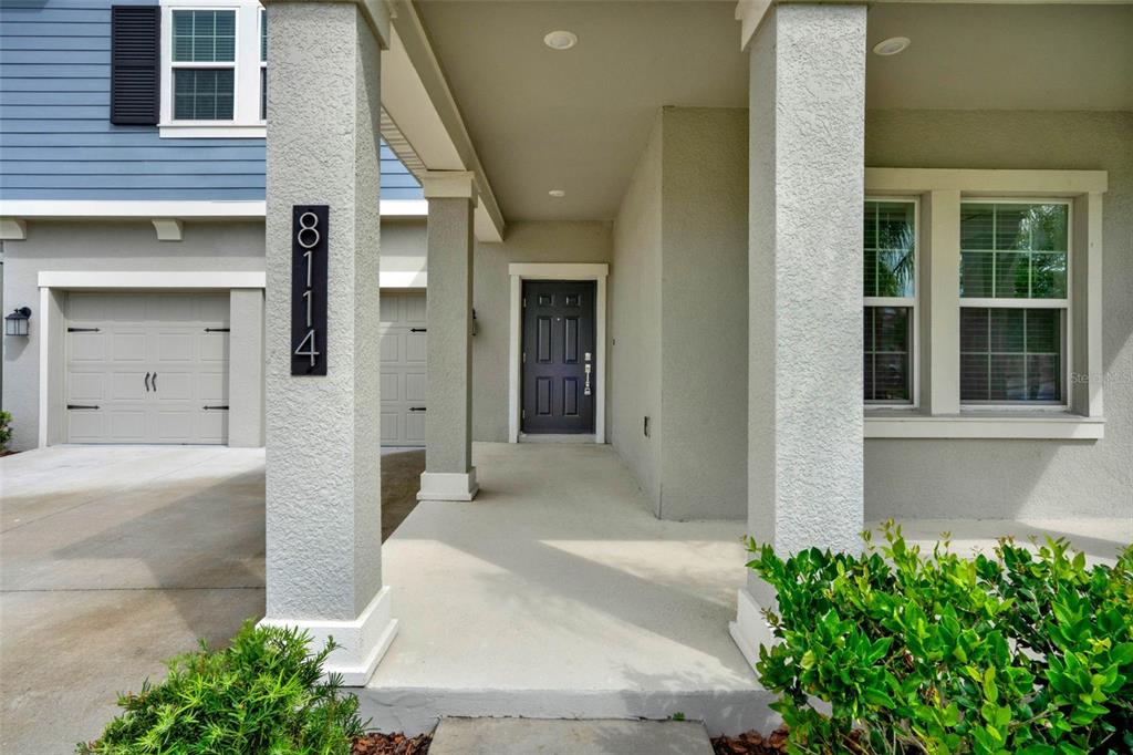 A covered front porch leads to a dark front door with a house number sign — 8114 SAYINGS DRIVE, WINTER GARDEN, FL