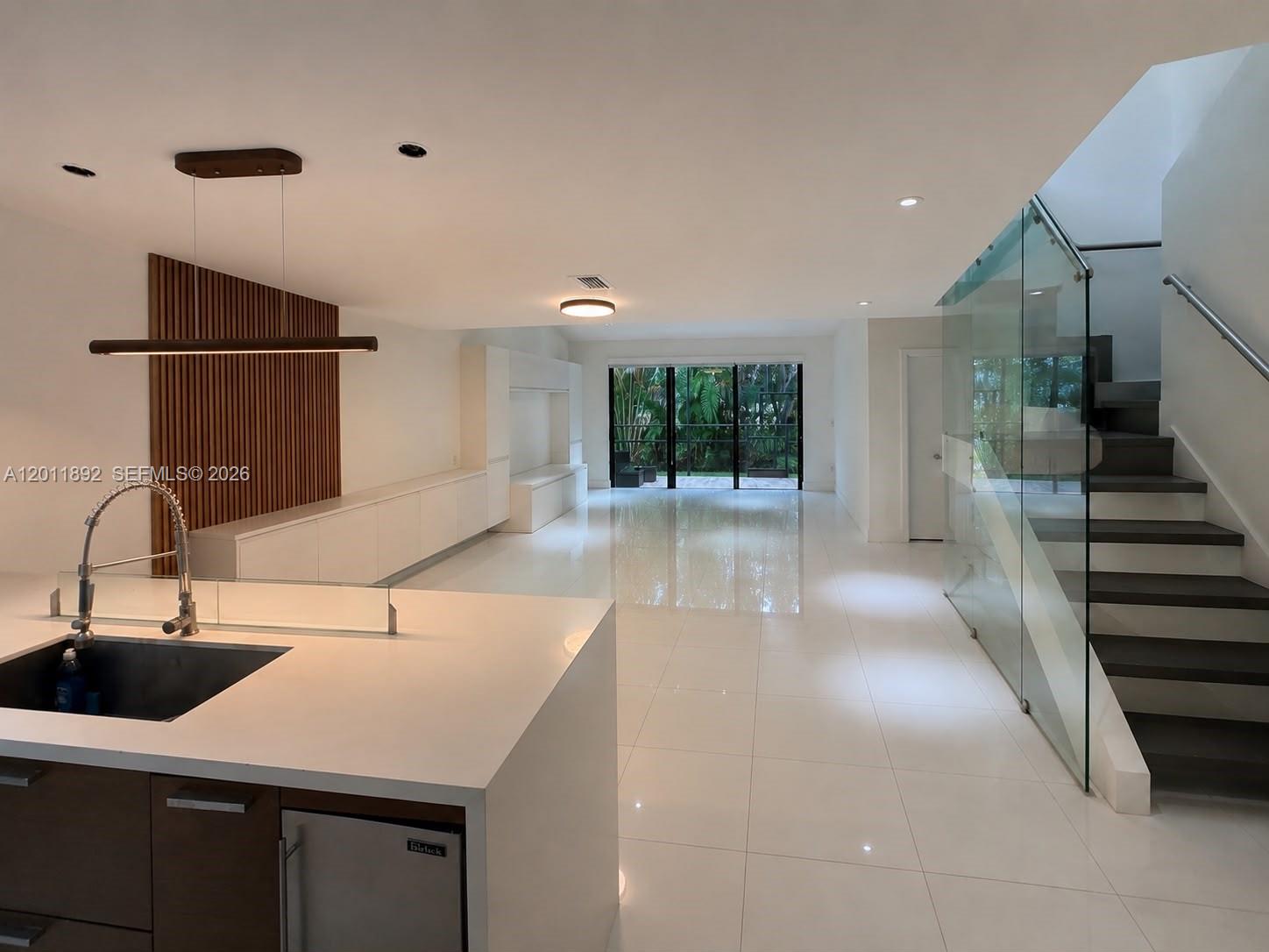 A modern open-concept living area features a kitchen island, white tile floors, and a staircase — 9871 NW 52nd Ln # 0, Doral FL 33178, DORAL, FL