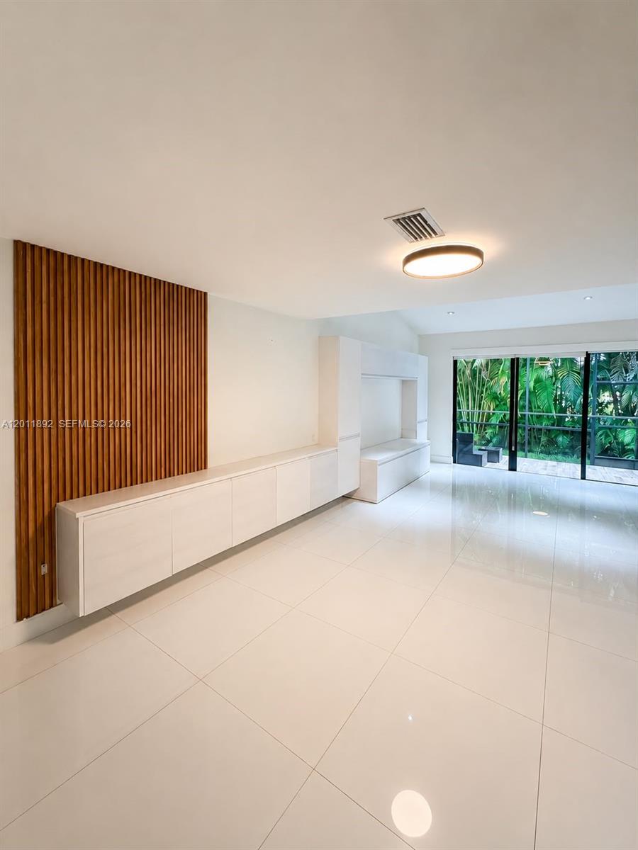 A modern living room features white tile floors, built-in cabinetry, and a wood slat accent wall — 9871 NW 52nd Ln # 0, Doral FL 33178, DORAL, FL