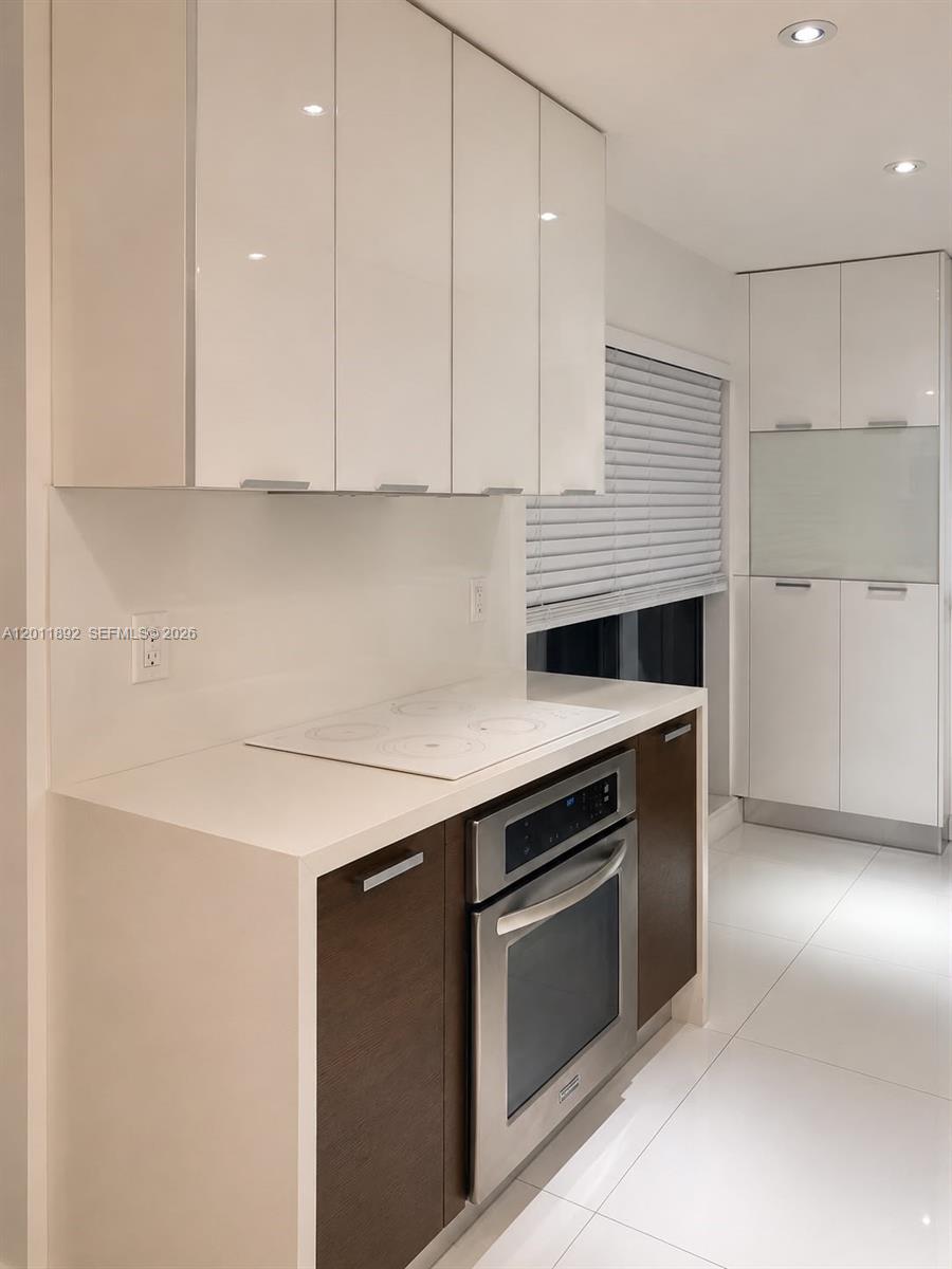 A modern kitchen features white upper cabinets, dark lower cabinets, and a built-in oven — 9871 NW 52nd Ln # 0, Doral FL 33178, DORAL, FL