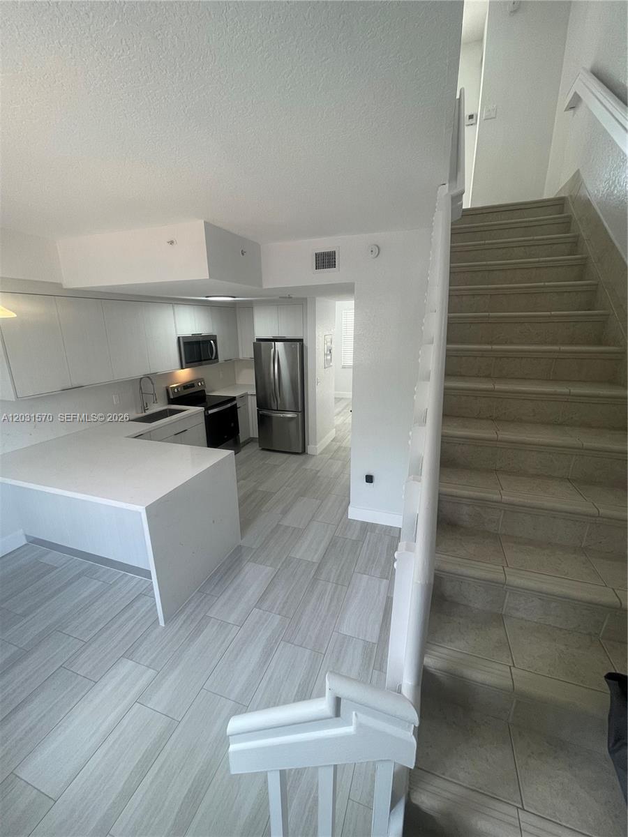 A bright room features light wood-look tile flooring, two windows, and a glass-paned door — 77 E 4th St # A212, Hialeah FL 33010, HIALEAH, FL