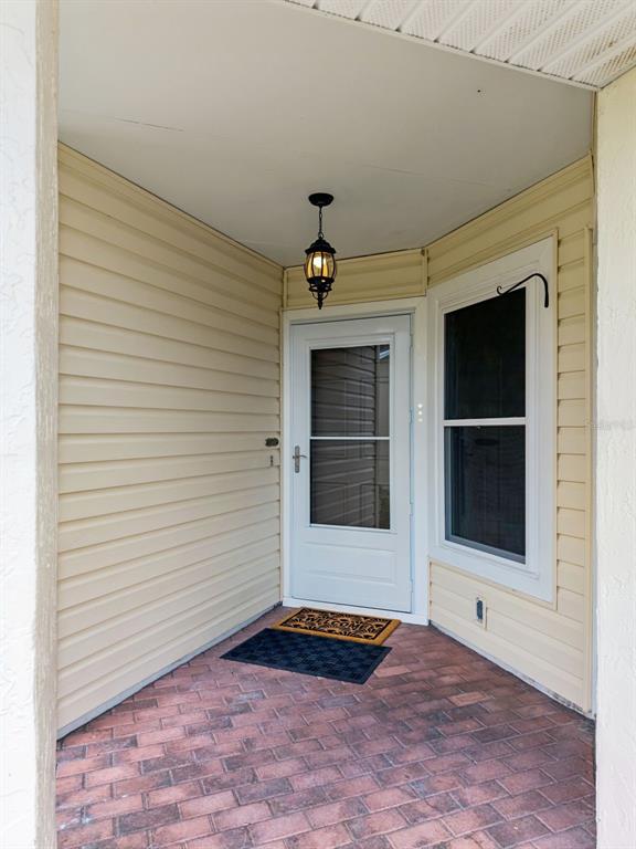 A covered entryway features light-colored vinyl siding, a brick floor, and a white storm door — 467 CIDERMILL PLACE, LAKE MARY, FL