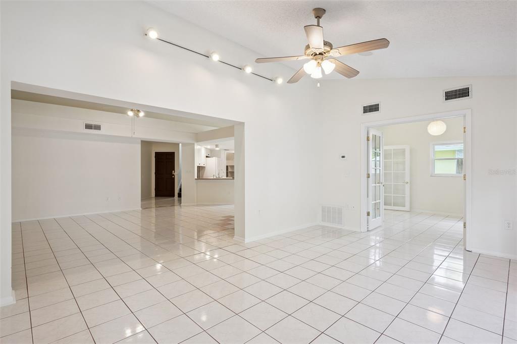A bright, open-concept living area features white tiled floors, a vaulted ceiling, and track lighting — 467 CIDERMILL PLACE, LAKE MARY, FL