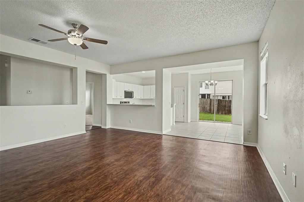 An open-concept living room features wood-look flooring, a ceiling fan, and a view into the kitchen — 4542 GALLBERRY COURT, ORLANDO, FL