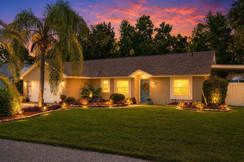 A single-story house with a blue front door, palm tree, and landscaped yard at sunset — 322 WINDWARD WAY, DAVENPORT, FL