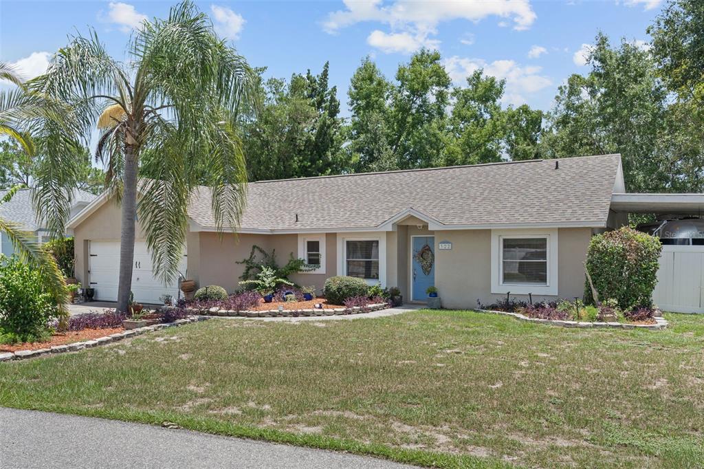 A single-story house with a light-colored exterior, a blue front door, and a palm tree — 322 WINDWARD WAY, DAVENPORT, FL