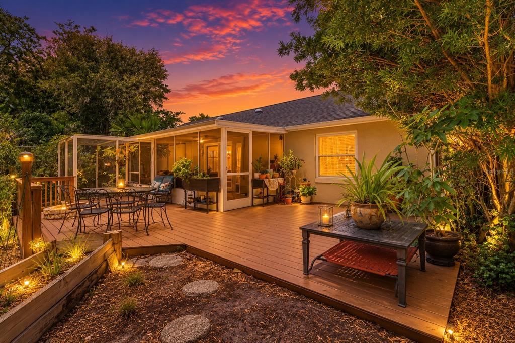 A wooden deck with outdoor furniture and a screened-in porch at sunset — 322 WINDWARD WAY, DAVENPORT, FL