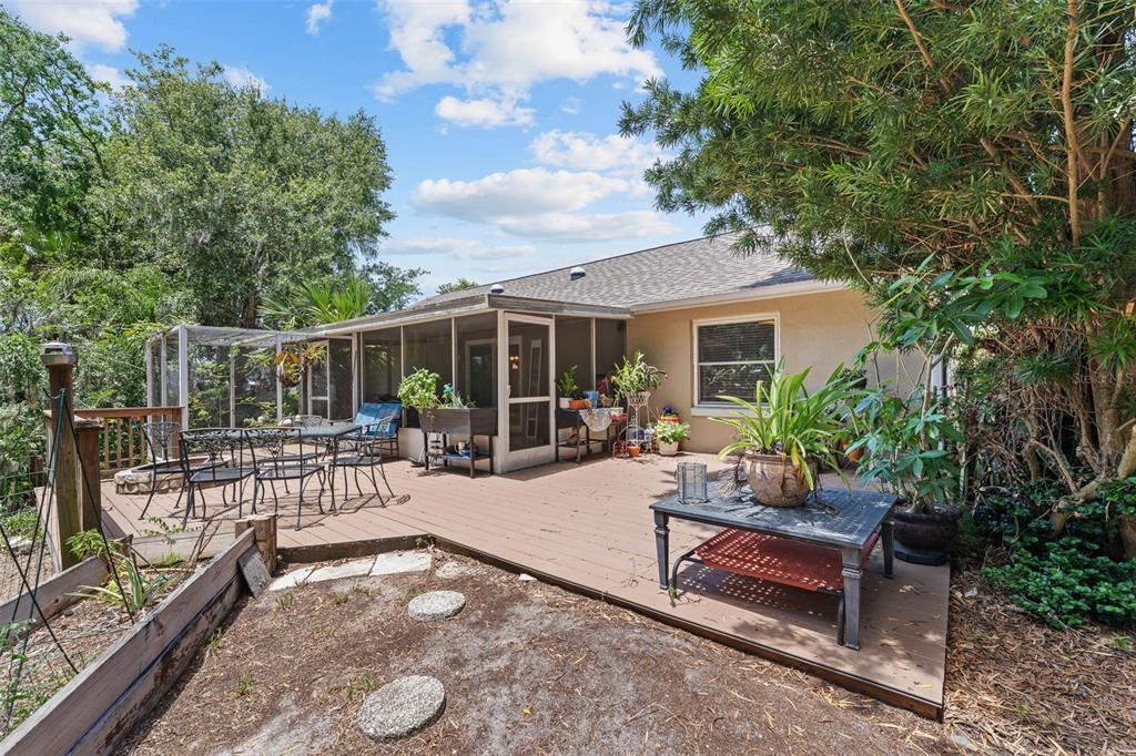 A wooden deck with outdoor furniture sits behind a house with a screened-in porch — 322 WINDWARD WAY, DAVENPORT, FL