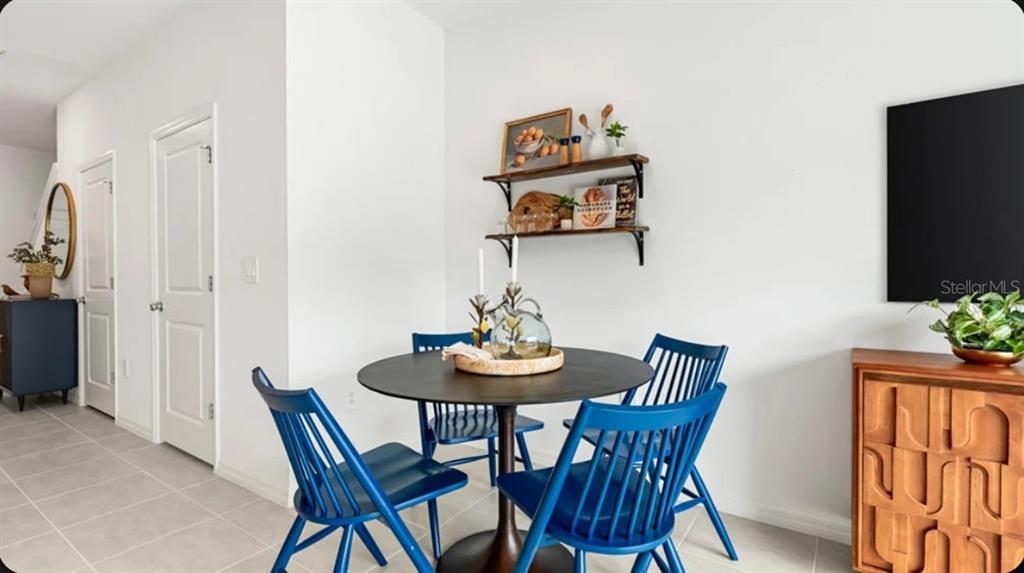 A dining area features a round table with four blue chairs and wall-mounted shelves — 10713 ECLIPSE STREET, SARASOTA, FL